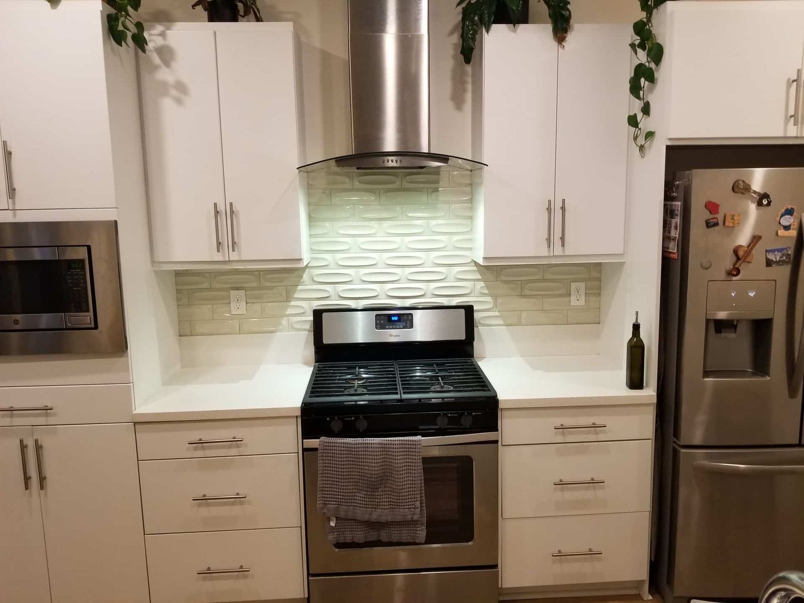 White scalloped tile backsplash behind gas range with vent hood