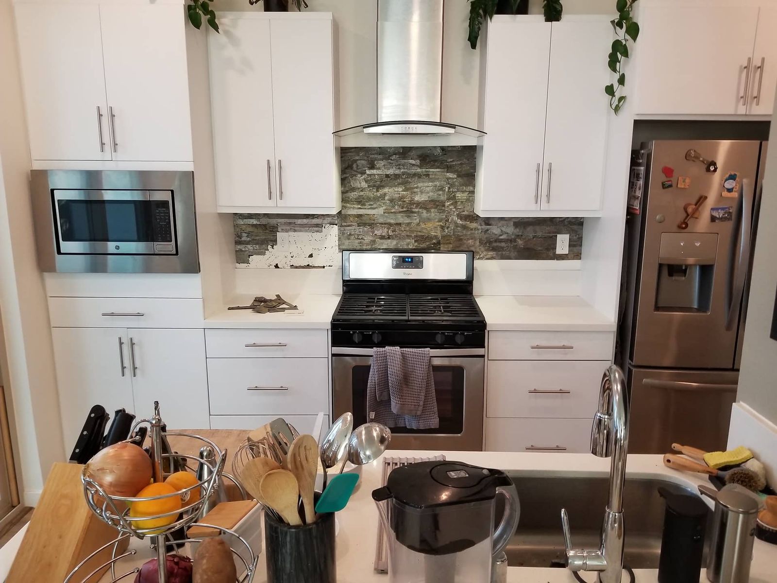 Before: Stacked stone tile backsplash behind gas range in white kitchen