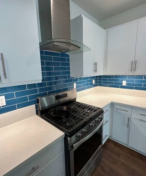 Blue subway tile backsplash behind stove in white kitchen