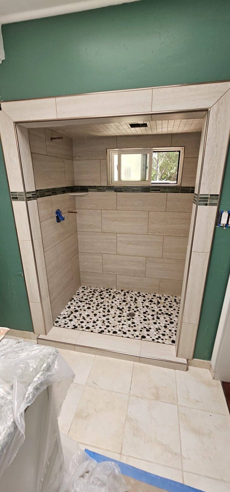 Tiled shower stall with pebble tile floor and window
