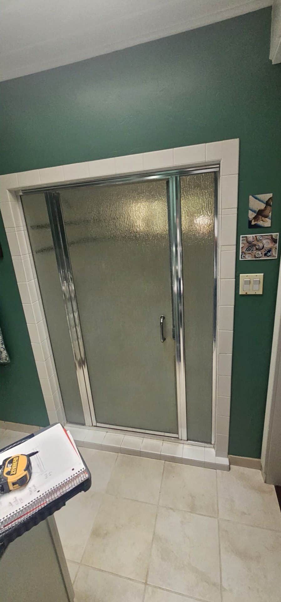 Framed glass shower door with textured glass and tile surround