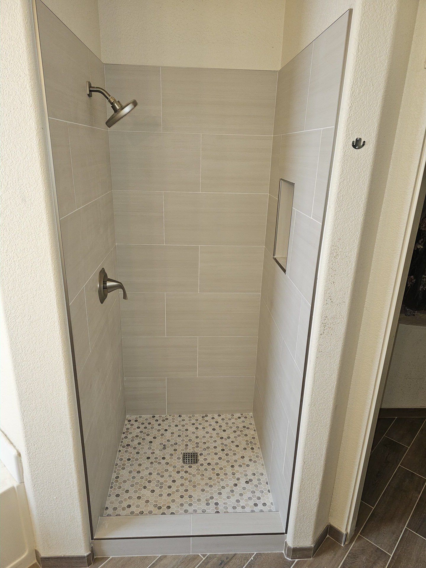 Tiled shower stall with gray subway tile and pebble mosaic floor