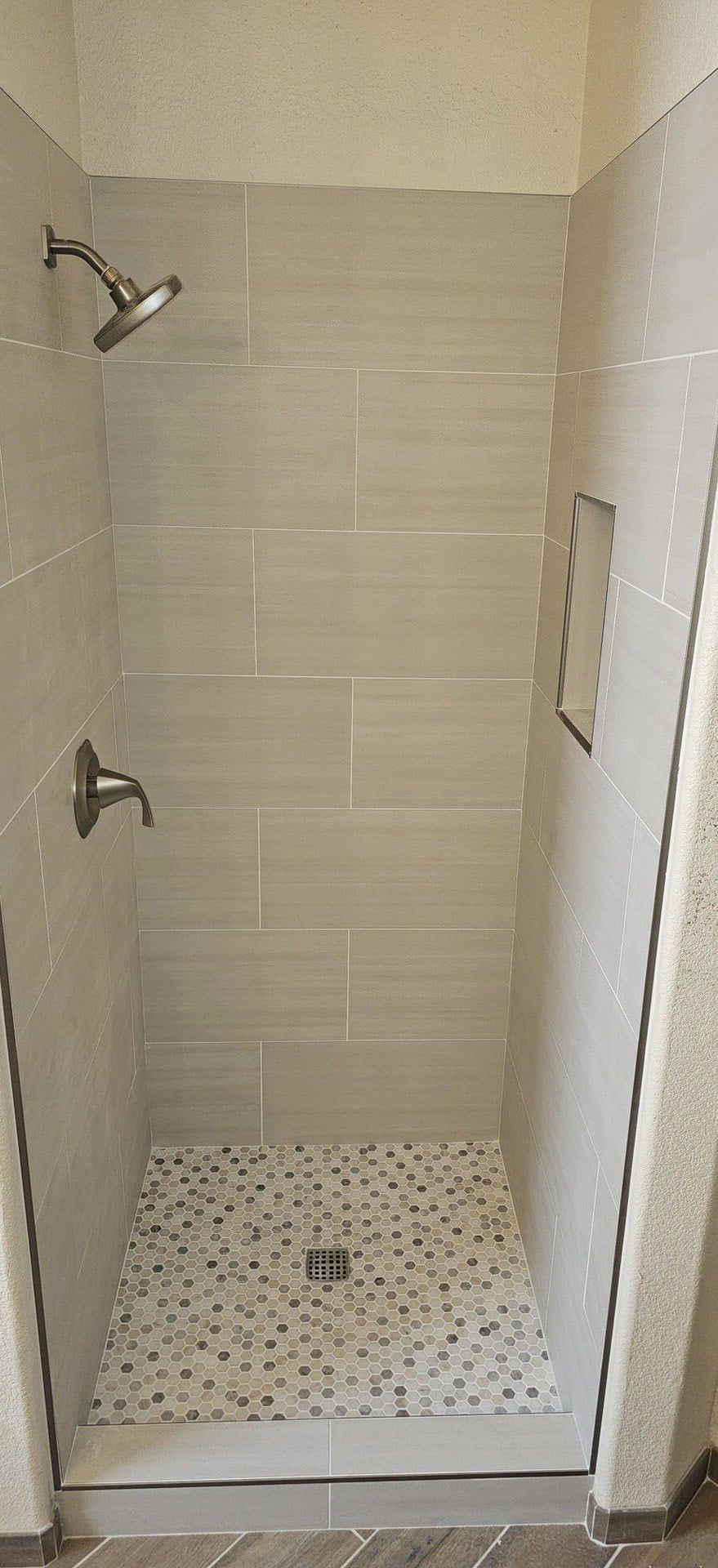 After: Gray subway tile shower with hexagon mosaic floor and niche