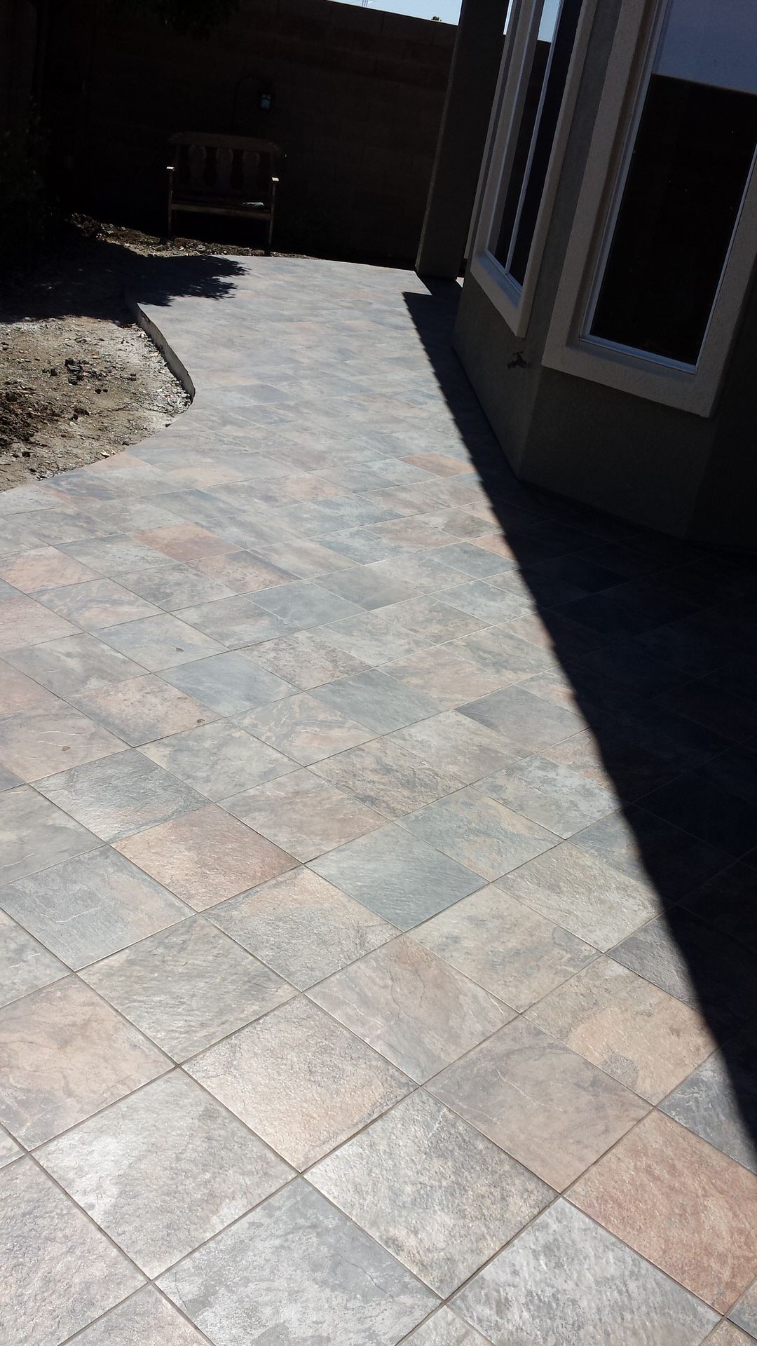 Diagonal laid stone-look tile walkway beside house exterior
