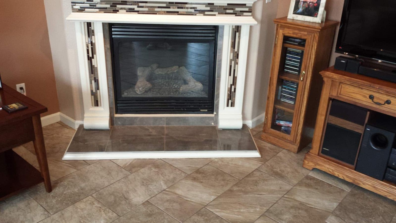 Gas fireplace with white mantel, glass mosaic tile accents, and tile hearth