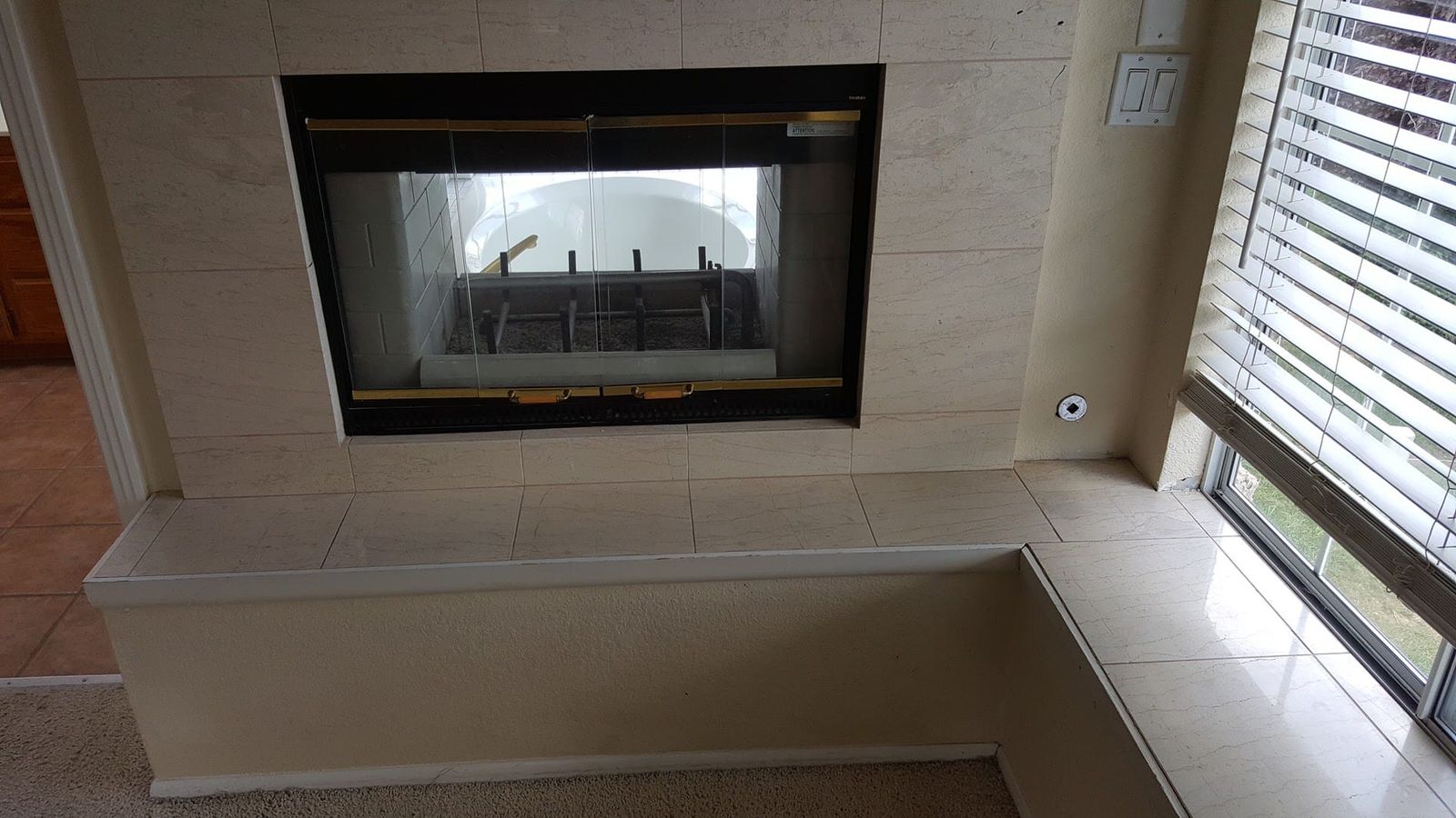 Tiled fireplace surround with black glass doors and raised hearth