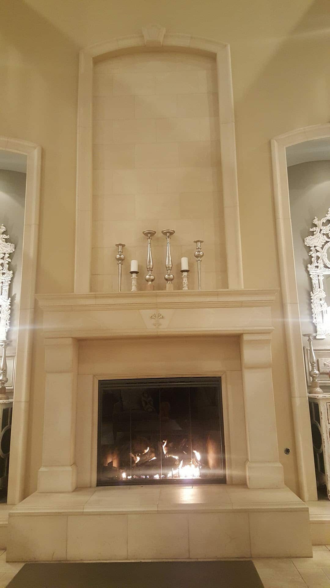 Cream stone fireplace surround with tall arched niche above mantel