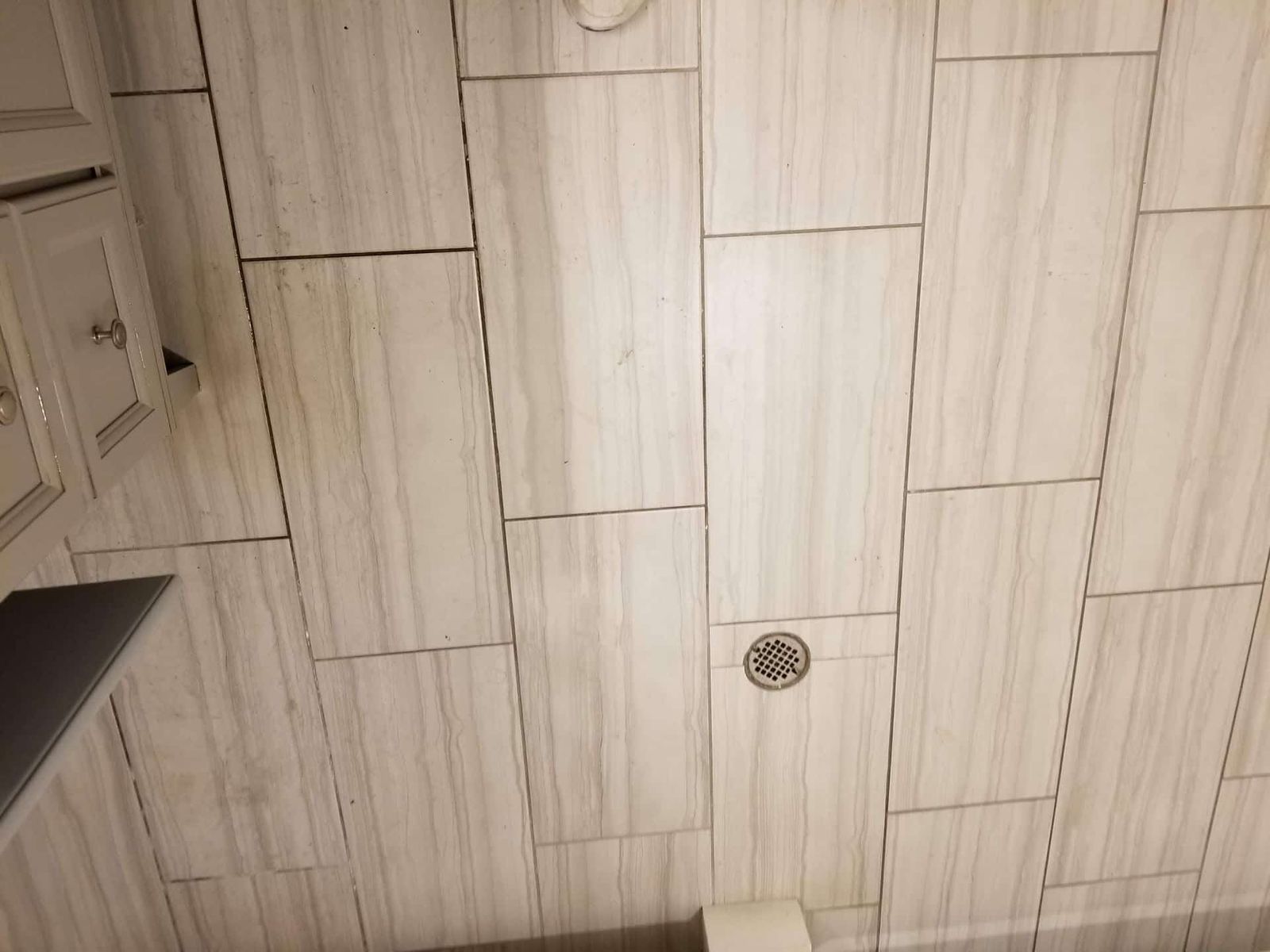Wood-look plank tile floor with round metal drain cover
