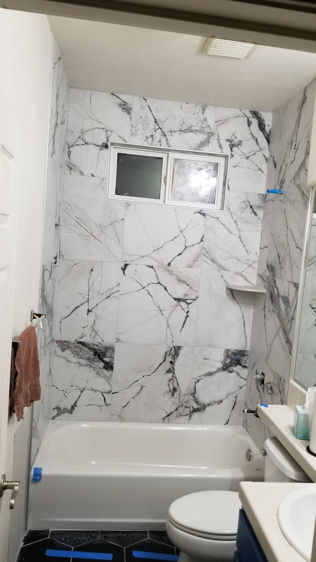 Marble-look tile tub surround with window and corner shelf niche