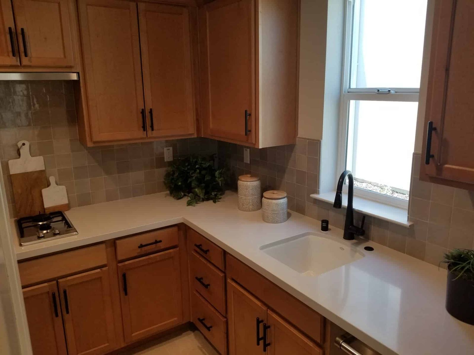 Kitchen with gray square tile backsplash and wood cabinets