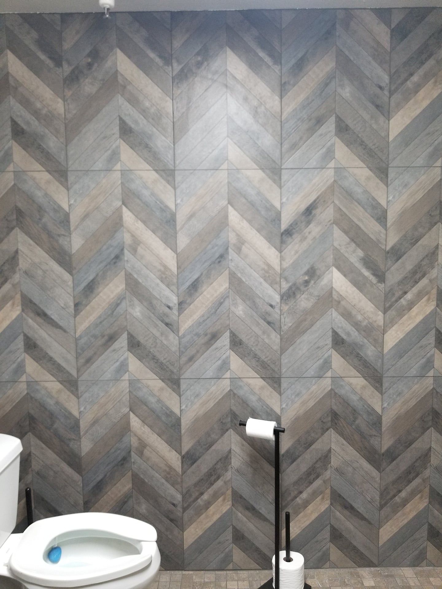 Chevron pattern wood-look tile wall behind toilet