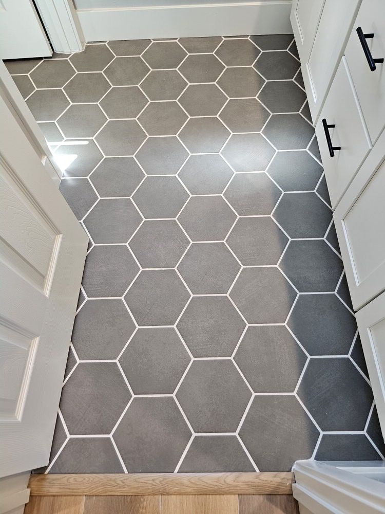 Gray hexagon tile floor with white grout near white cabinets