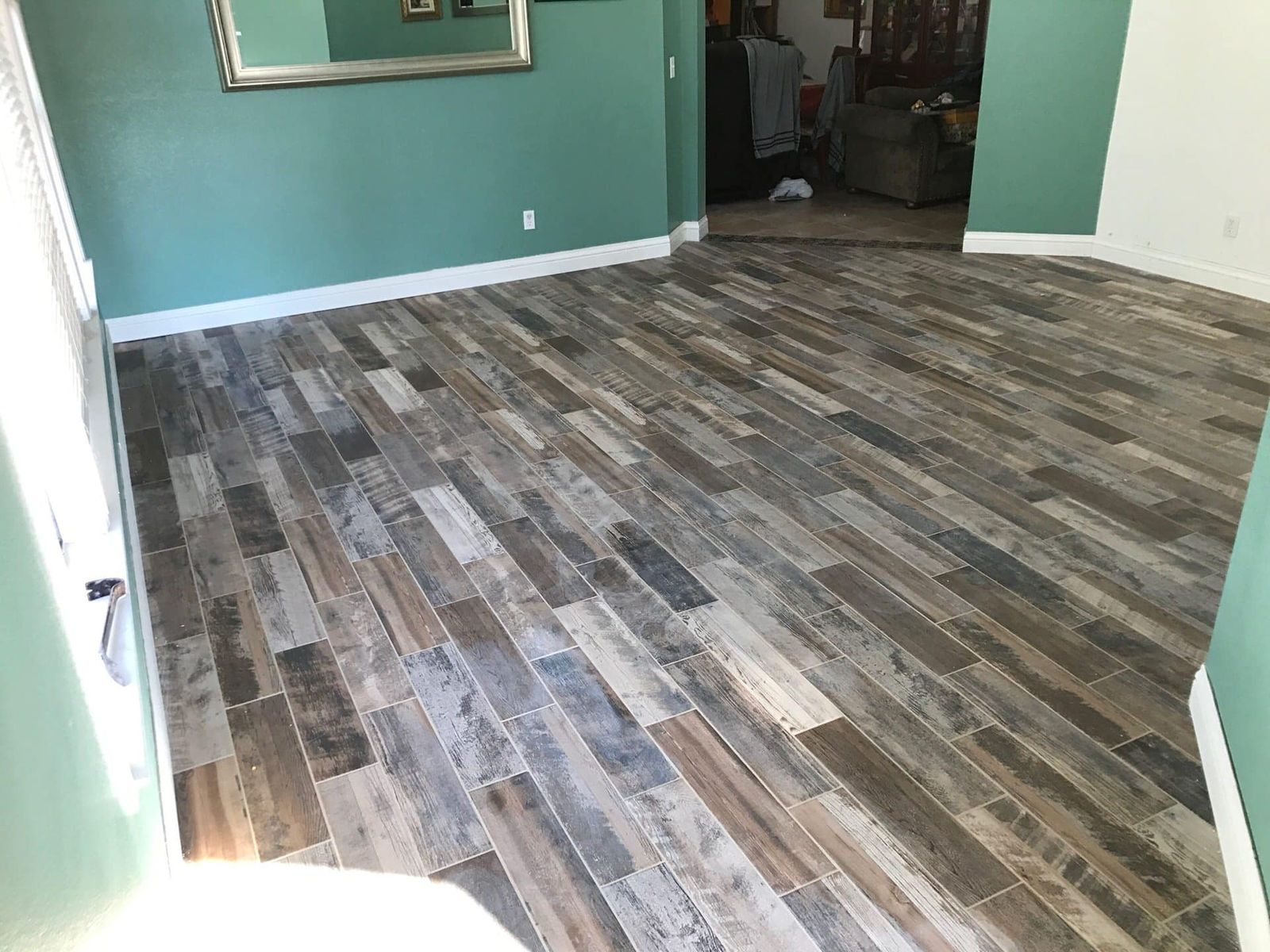 Wood-look plank tile floor in living room with teal walls