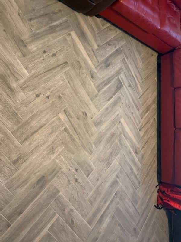 Herringbone wood-look tile floor beside red leather sofa