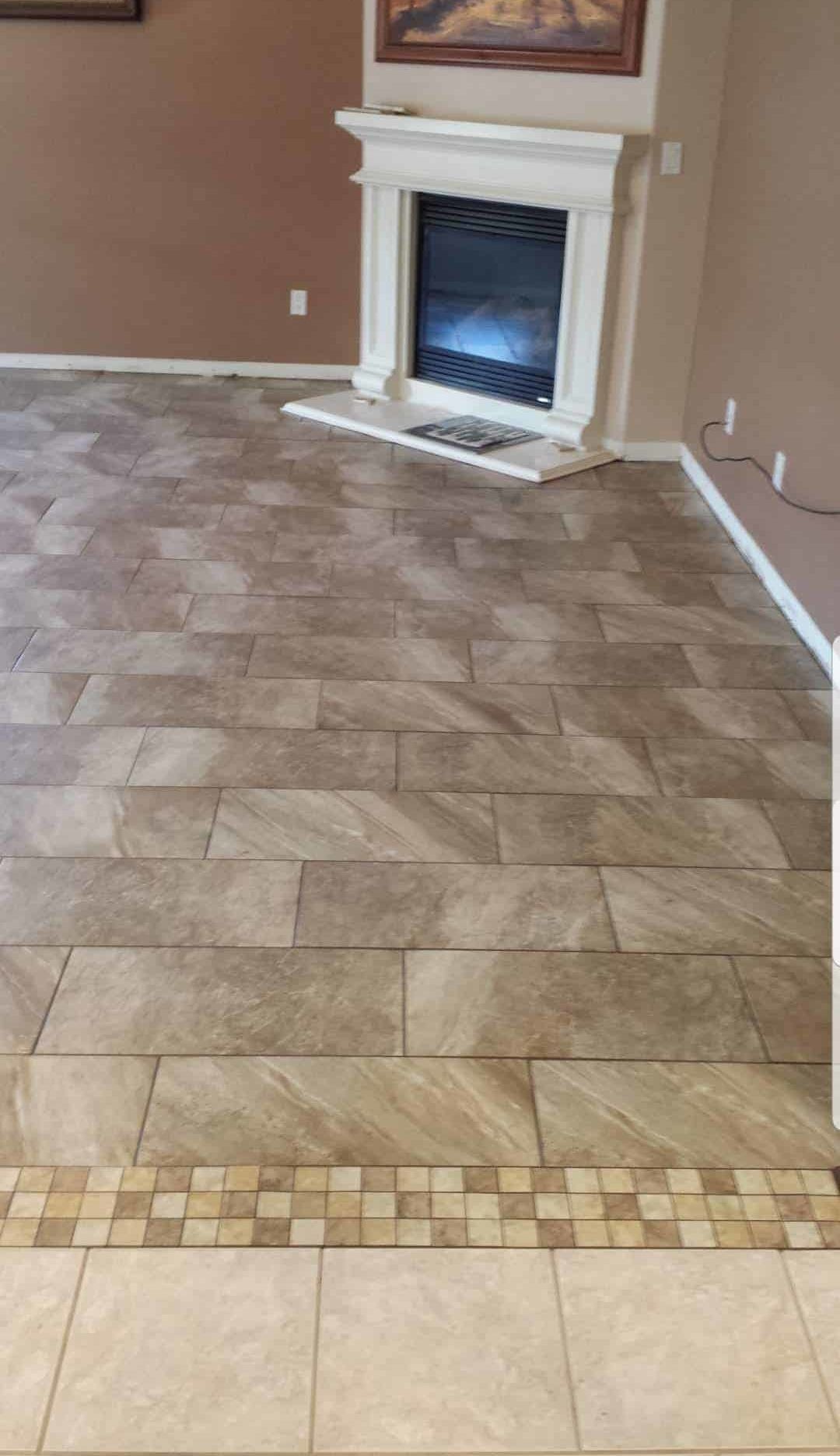 Large plank-style tile floor with mosaic transition strip near fireplace
