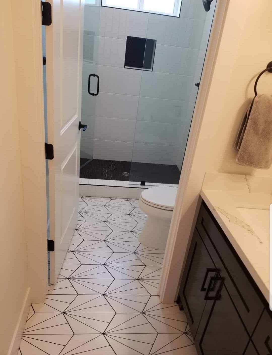 Bathroom with geometric star-pattern tile floor and glass shower