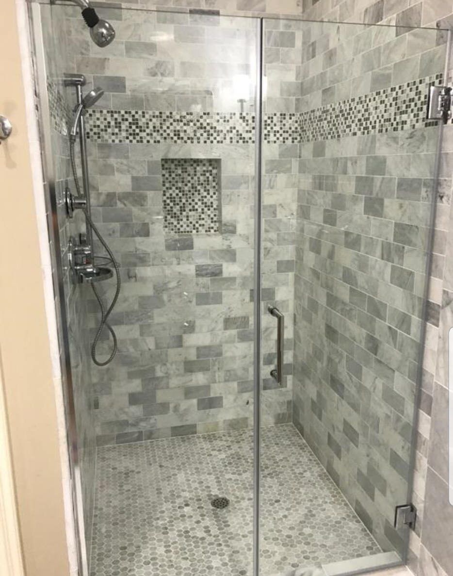 Glass-enclosed shower with gray subway tile and mosaic accent strip