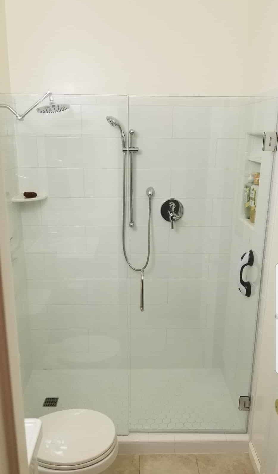 Glass-enclosed shower with white subway tile and hexagon floor tile