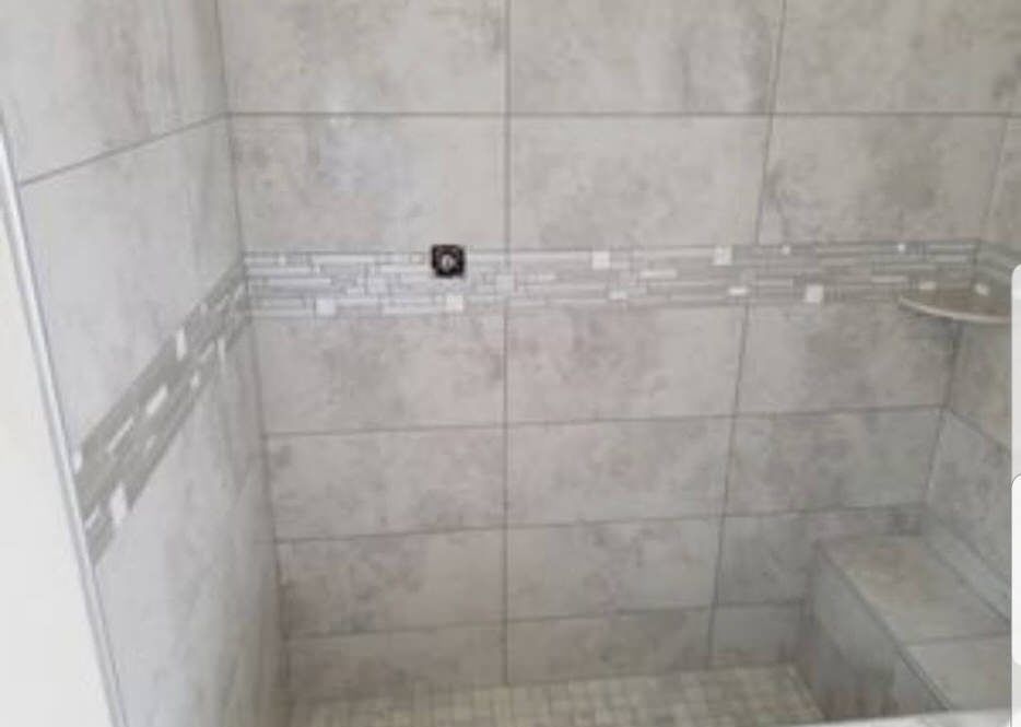Gray tiled shower with mosaic accent strip and built-in bench