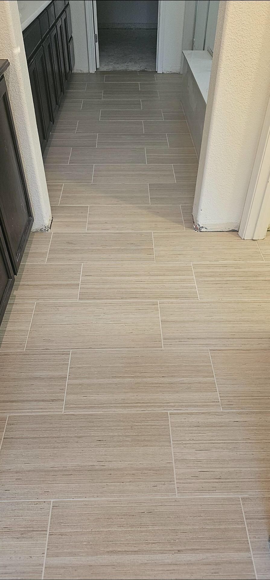 Plank tile floor in hallway with dark wood cabinets